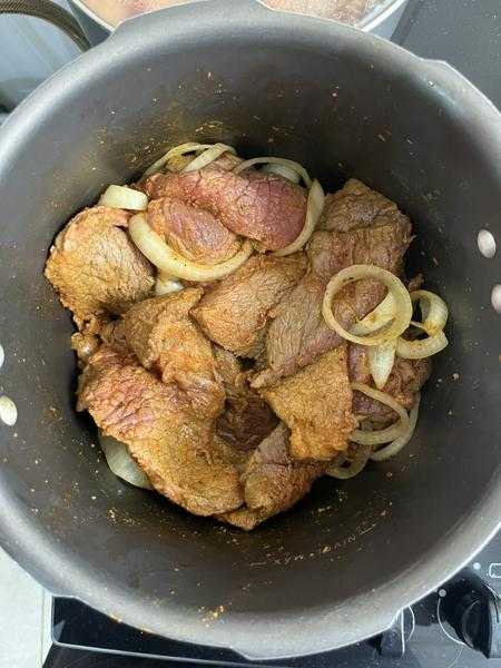 Em uma panela de pressão aqueça a manteiga. Adicione a carne e as cebolas e refogue por 5 minutos.